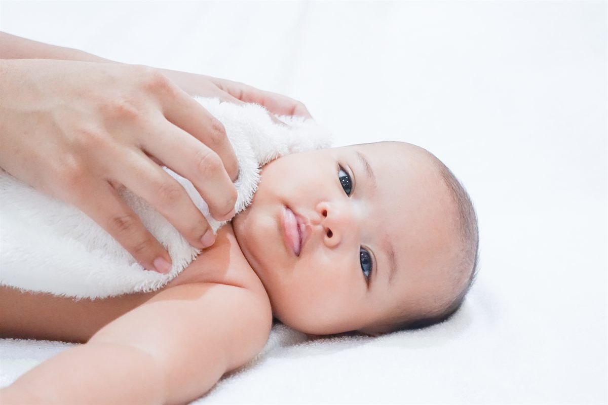 Parent gently drying a calm baby with a CÂLINE organic cotton washcloth